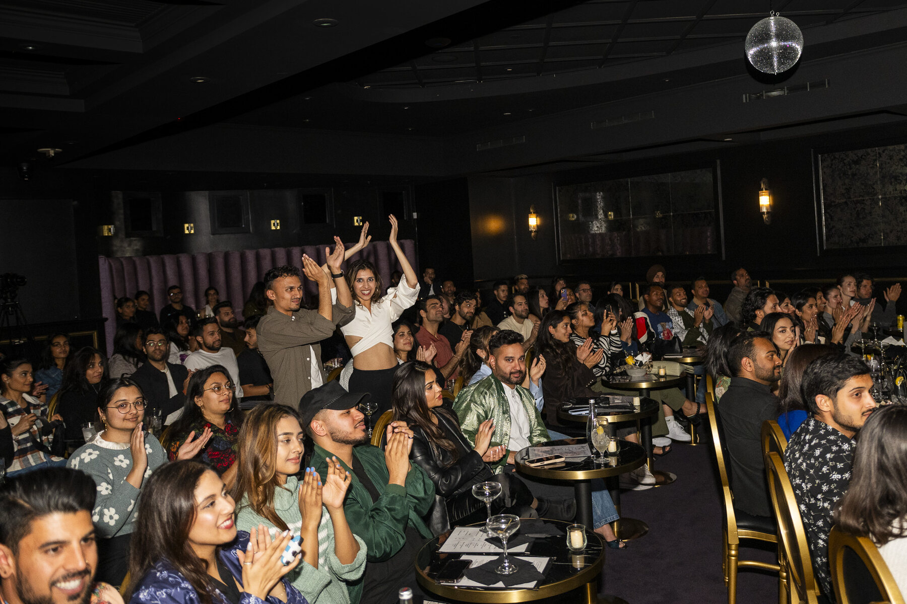 A packed audience applauding at one of Priya's comedy shows